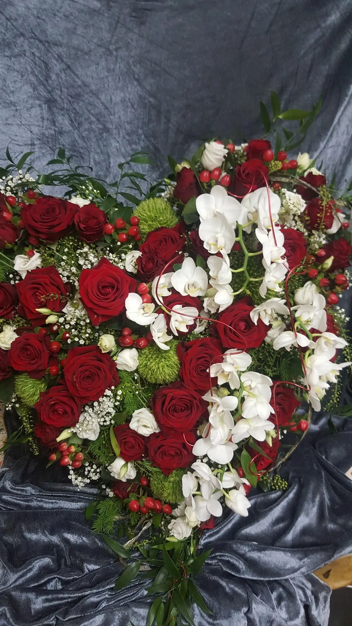 Dicht gestecktes Herz aus roten Rosen und weißen Blüten